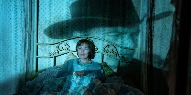 Photo of Olivia Colman as Susan lying in bed with an image of Gary Cooper from "High Noon" projected on the wall behind her.