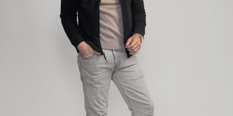 man wearing black bomber jacket with gray jeans and sneakers