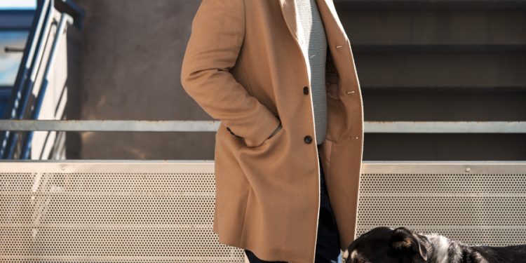 scandinavian men's style outfit inspiration with camel topcoat, sweater, watch cap, and white sneakers