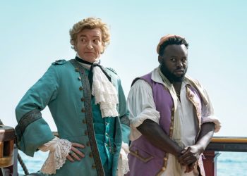 Foppish "gentleman pirate" Stede (Rhys Darby), left, with his crew member Oluwande (Samson Kayo), right, stand on the deck of a ship.
