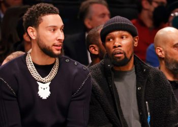 Ben Simmons sits on the Nets bench next to Kevin Durant