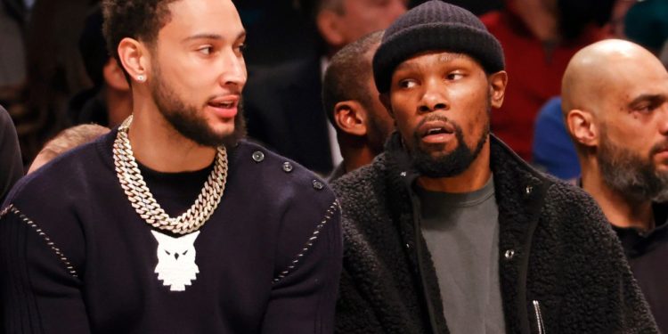 Ben Simmons sits on the Nets bench next to Kevin Durant